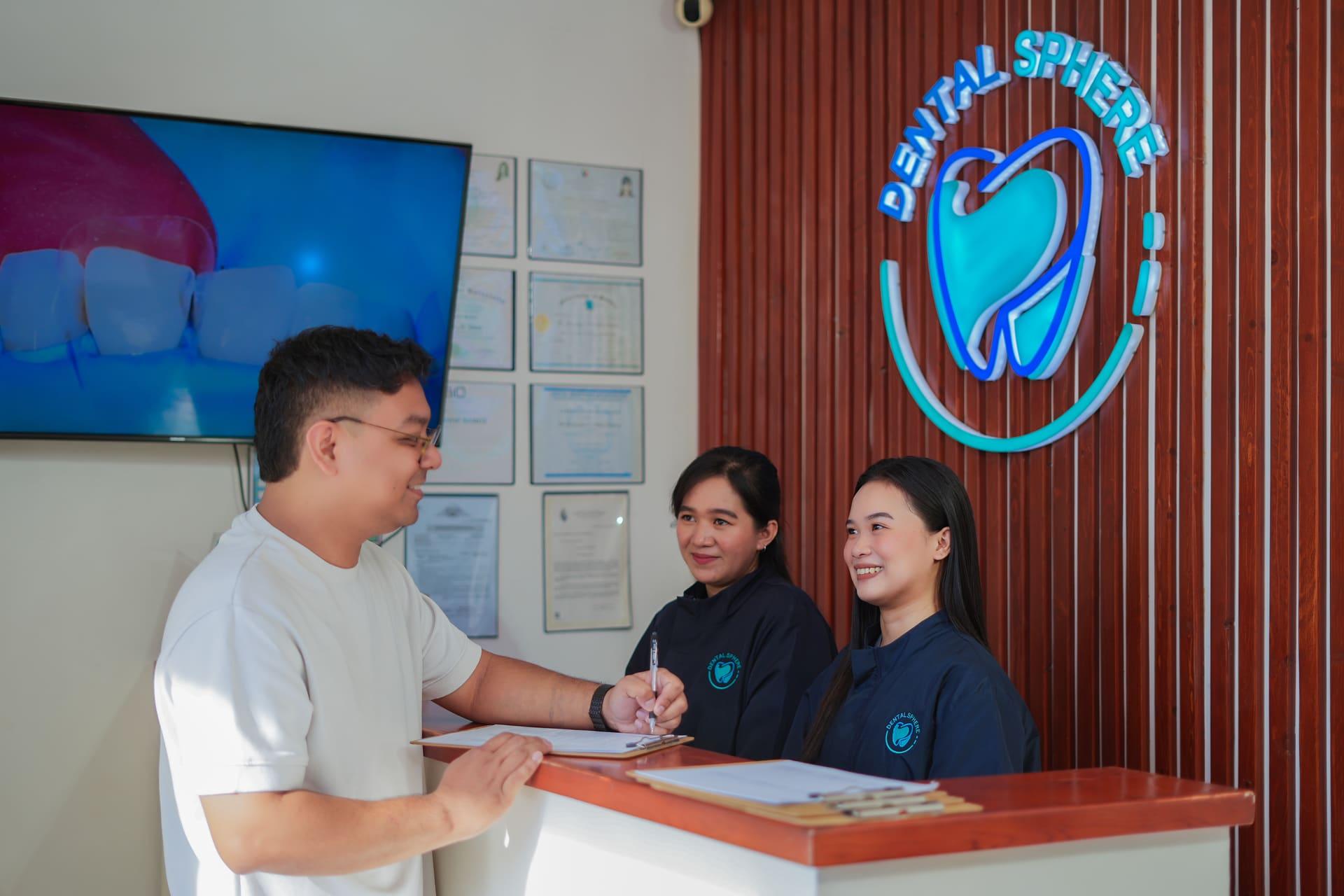 A patient being welcomed at the Dental Sphere reception desk